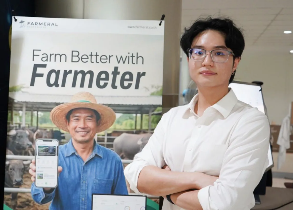 Worakorn beside a Farmeter poster