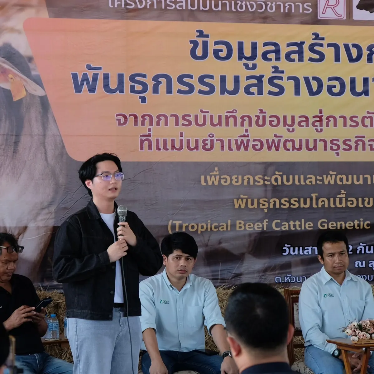 Worakorn on stage with a microphone at a beef cattle seminar
